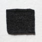 A small sample of black and dark grey yarns knitted to create a soft marl