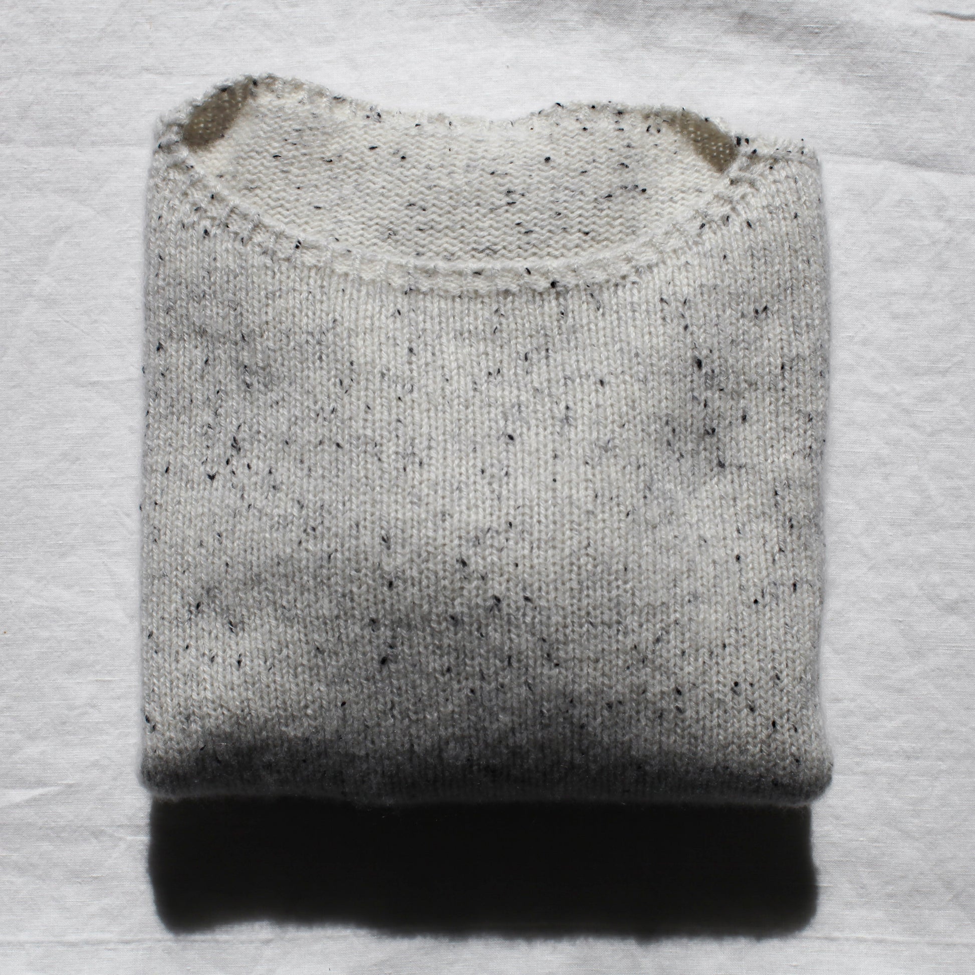 The Summer Soft jersey is folded neatly on a white linen table cloth. The light is shining softly from the top.