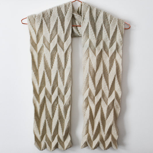 An Ups and Downs scarf hanging from a hanger against a neutral background. The shadows from the side make the 3D fabric stand out