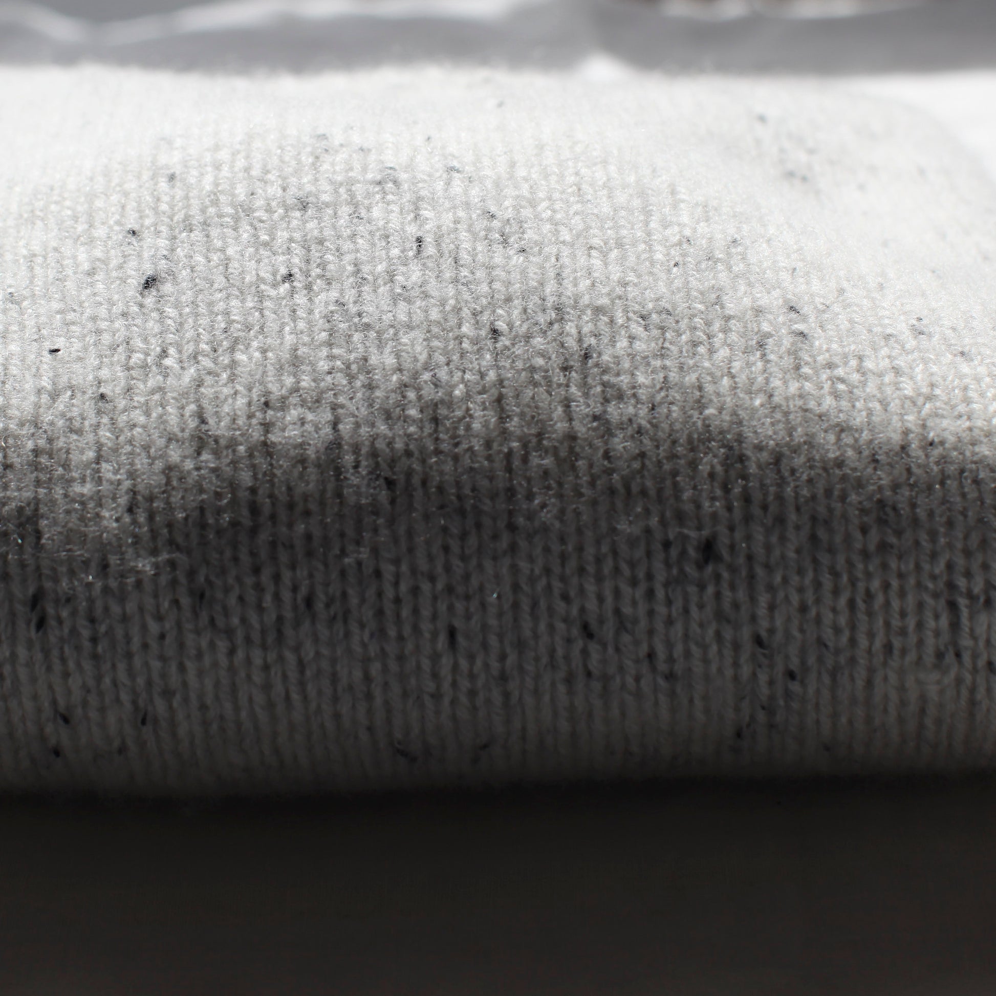 A close up of the fabric forming the Summer Soft jersey. The light is shining on half the jersey, with the edge of the shadow in the centre of the photo.
