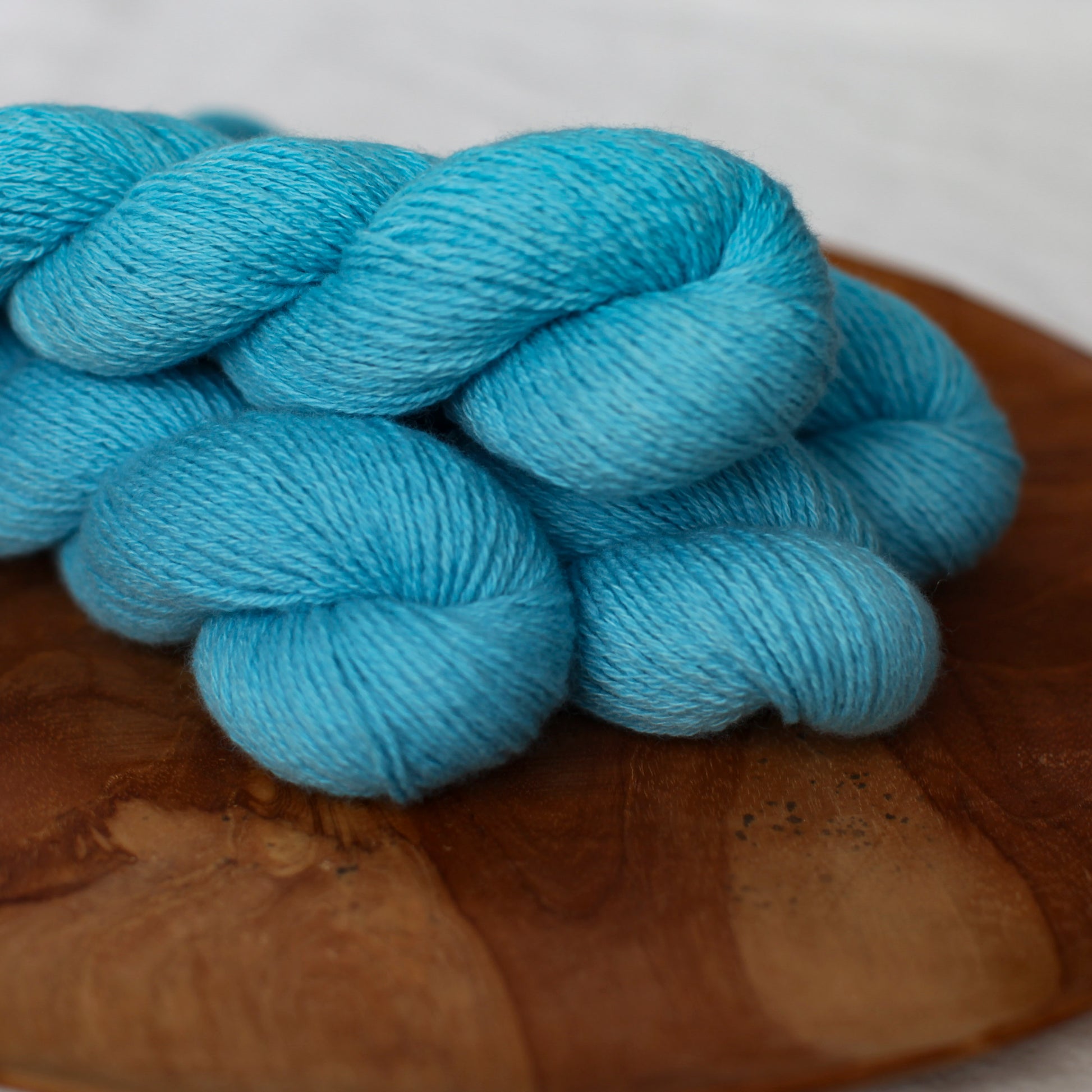 A few skeins in deep sea ice blue on a wooden board with a white background
