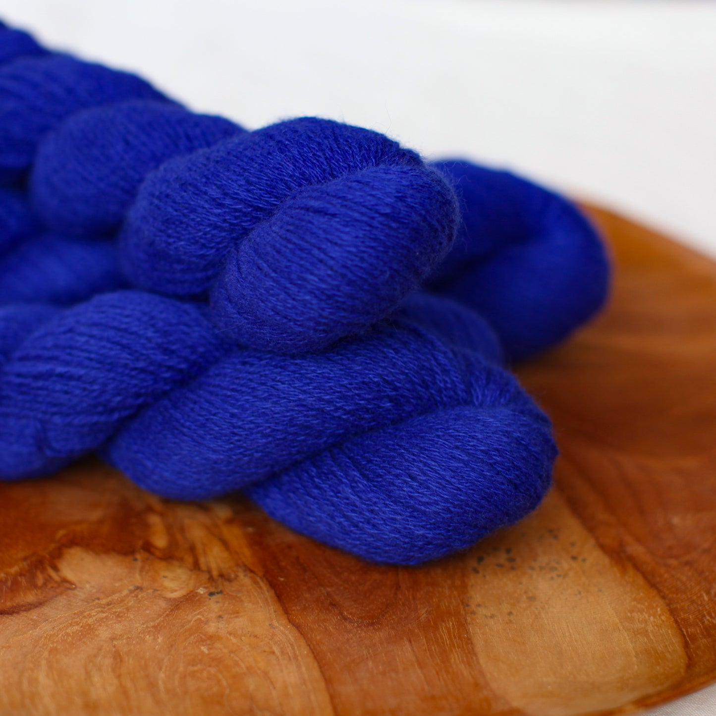 A few skeins in deep ultramarine blue on a wooden board with a white background